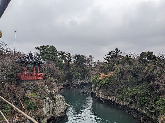 River surrounded by greenery and a small red oriental building