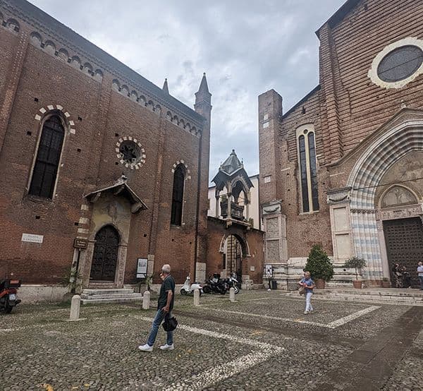Two red brick buildings with white patterns around windows in a cobbled square